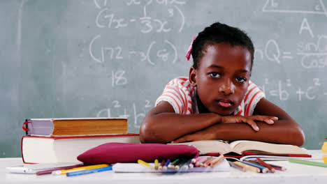 schoolgirl relaxing on an open book in classroom