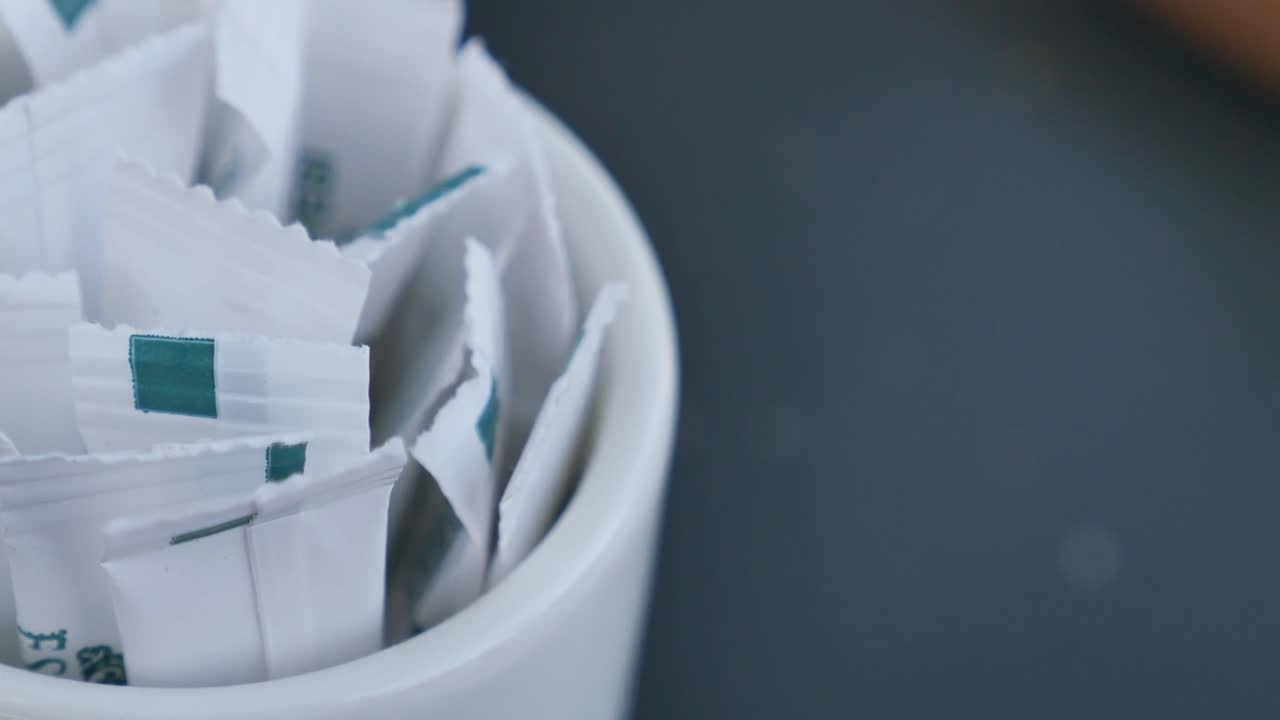 un recipiente de cerámica blanca lleno de paquetes individuales de azúcar