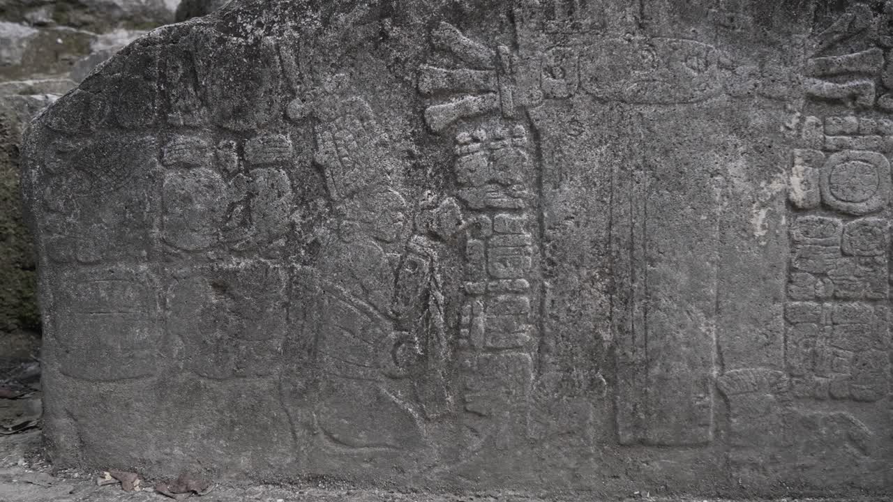 Detailed carvings on a stone slab showcase ancient Mayan artistry and symbols. The artwork features figures and hieroglyphs, revealing the culture's rich history and craftsmanship.