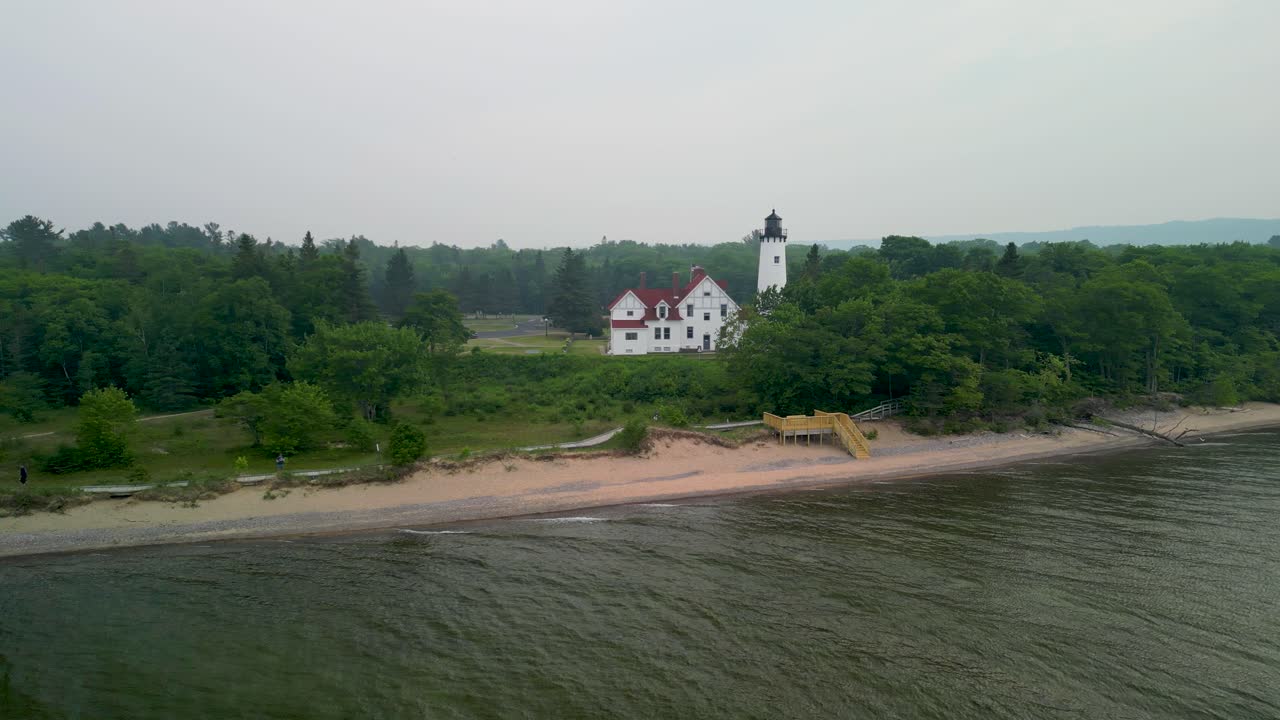 vista aérea del faro de point iriquois y la playa con humo de incendios forestales, lago superior, michigan