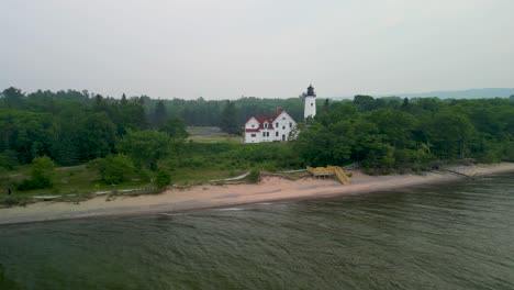 Vista-Aérea-Del-Faro-De-Point-Iriquois-Y-La-Playa-Con-Humo-De-Incendios-Forestales,-Lago-Superior,-Michigan