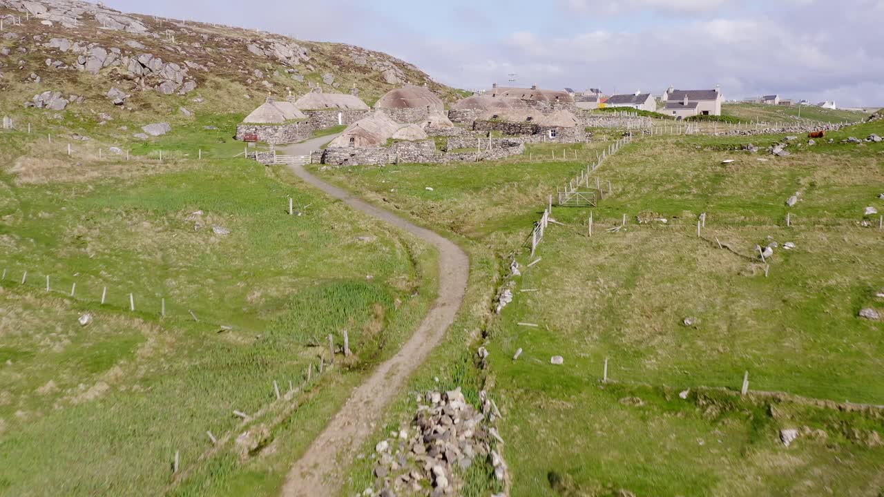 Ascending drone shot of the Gearrannan Blackhouse Village on the Isle of Lewis, part of the Outer Hebrides of Scotland
