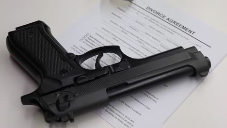 person-taking-a-handful-of-sleeping-tablets-then-picks-up-a-black-firearm-with-divorce-papers-left-visible-on-the-table