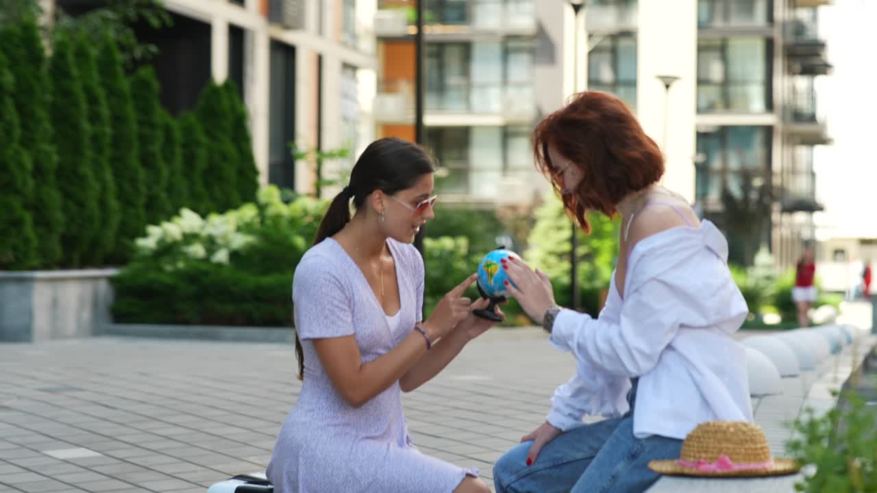 dos chicas examinando un globo al aire libre