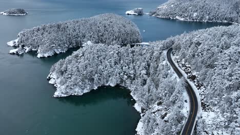 rising drone shot of deception pass state park covered in snow