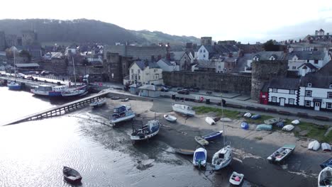 idyllic conwy castle and harbour fishing town boats on coastal waterfront aerial descending push in