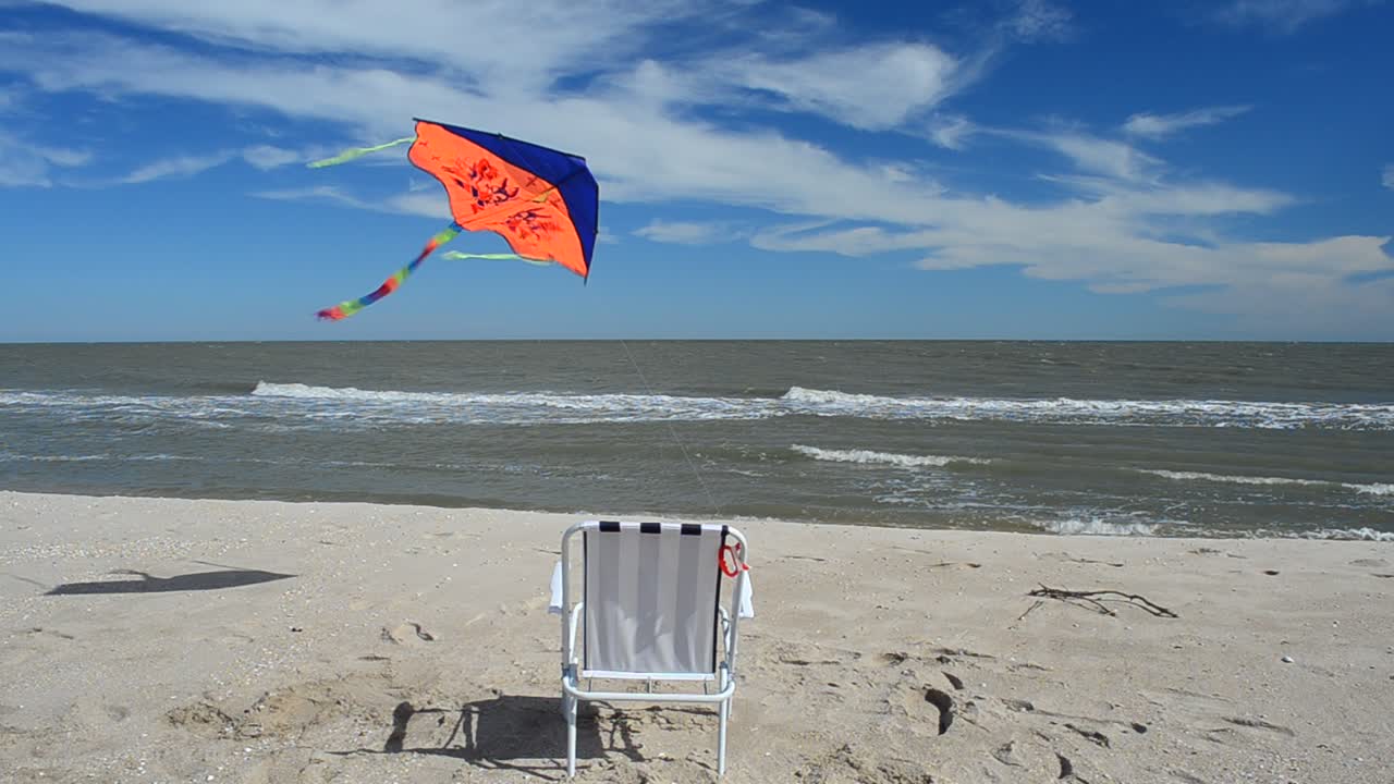 Liggestol på stranden, havet og en drage. Sommertid ved strandkanten
