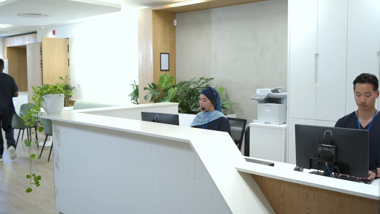 Diversi colleghi in camice che rispondono alle chiamate e digitano alla reception per gestire il check-in dei pazienti