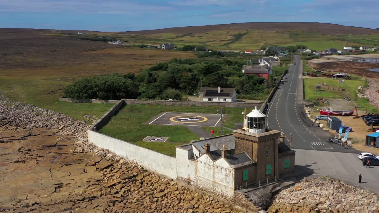 Dynamisk luftfoto, der trækker sig tilbage fra Blacksod Fyrs lanterne, og afslører Blacksod Bugt og en travl mole. Irland
