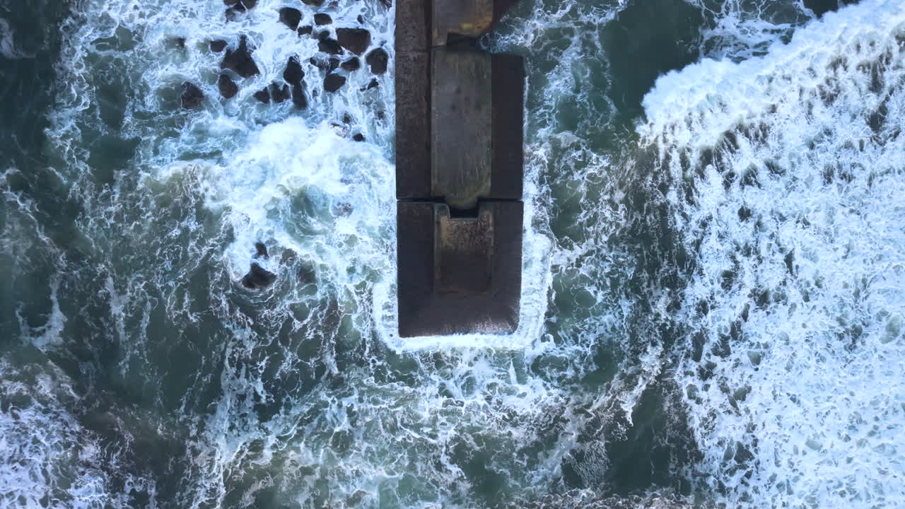 Top down view of a jetty. Waves crashing. Drone view.