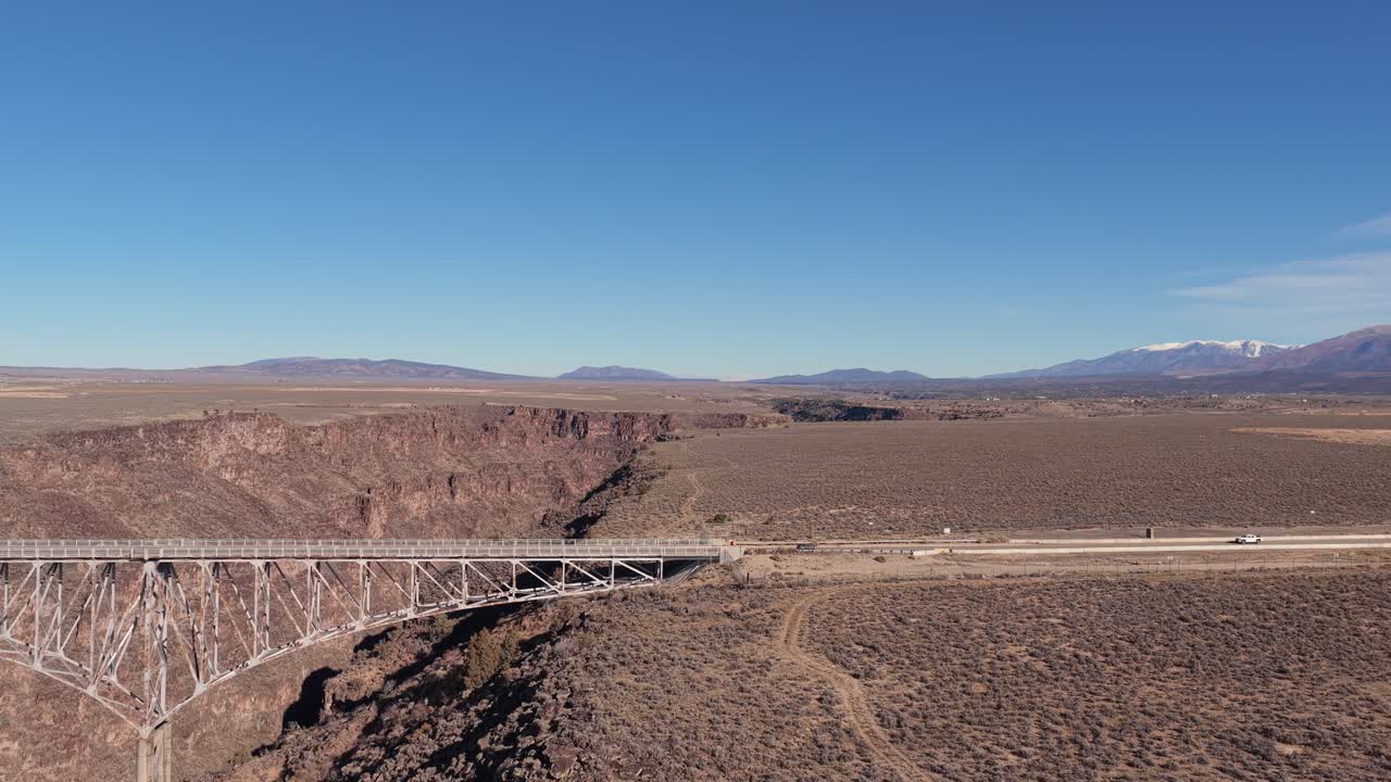 Capturing the single car as it finishes its crossing of the Rio Grande Gorge Bridge, moving onto the highway shoulder. An iconic Southwestern transportation landmark near Taos, New Mexico