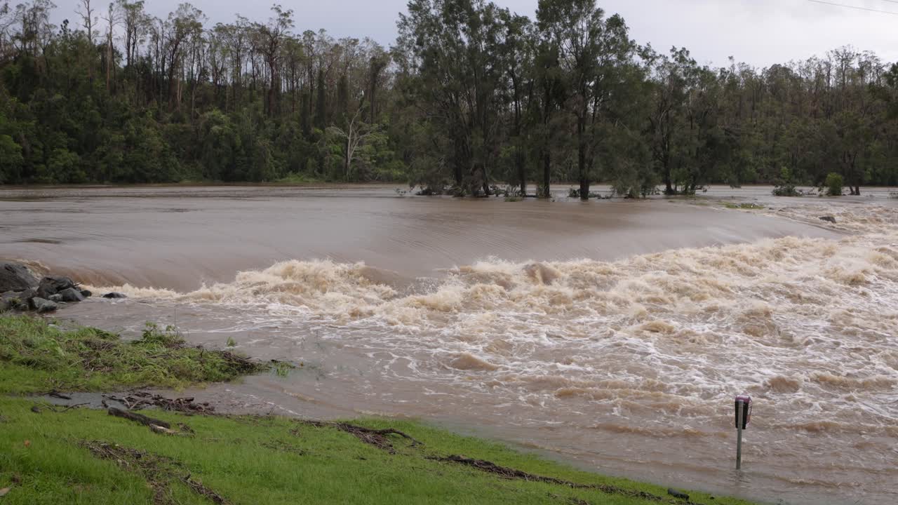 Coomera, Gold Coast, 2 January 2024 - Medium shot, Coomera River Causeway under flood waters from the 2024 Storms in January