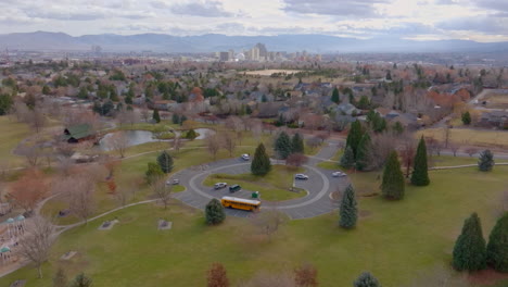 Aerial-of-a-school-bus-parked-at-a-park-with-a-neighborhood-and-city-of-Reno-in-the-background