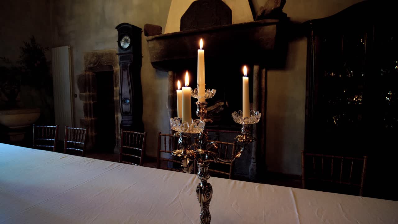 Suggestiva ripresa ad arco in primo piano di un portacandele antico e vintage con candele accese, posizionato su un tavolo di notte