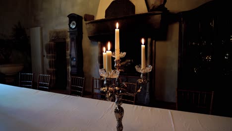 captivating close-up arc shot of vintage antique candle holder with candles burning placed on table at night