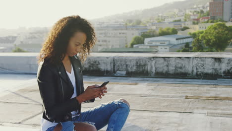 fashionable young woman on urban rooftop using smartphone