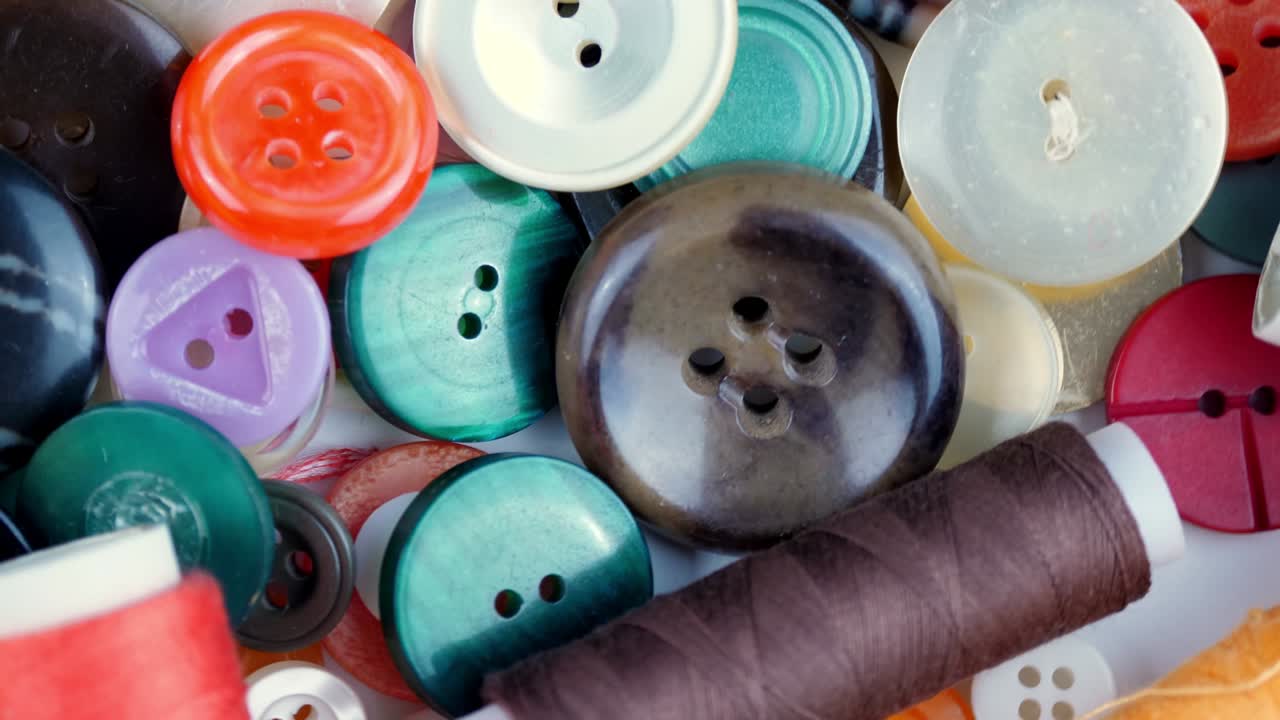 botones de costura. primer plano. rotación. varios botones de cosimiento de colores redondos giran en la mesa giratoria. fondo de movimiento de bucle. concepto de color, moda, confección, costura, sastre