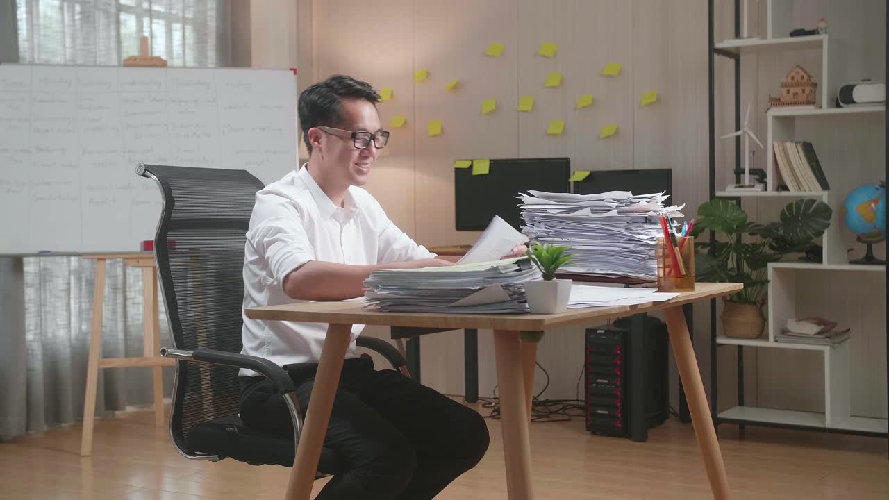 Happy Asian Man Celebrating Finishing Working With Documents At The Office