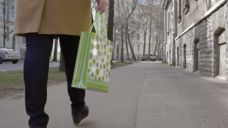 piernas de mujer caminando con una bolsa de compras colorida