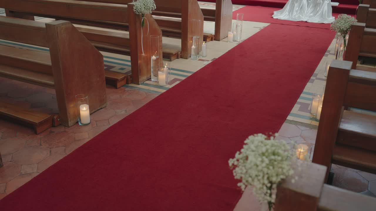 navata nuziale con tappeto rosso illuminata da candele all'interno di una chiesa