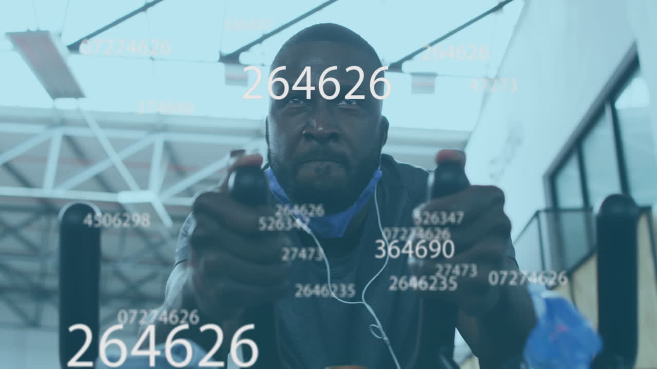 Animation of symbols changing over man with face mask exercising on elliptical bike in gym