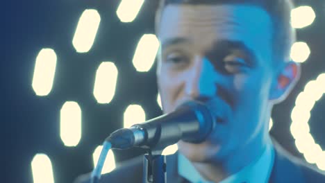 man singing song in microphone during performance on stage on rock concert. close up man rock star singer on music concert on colorful light background