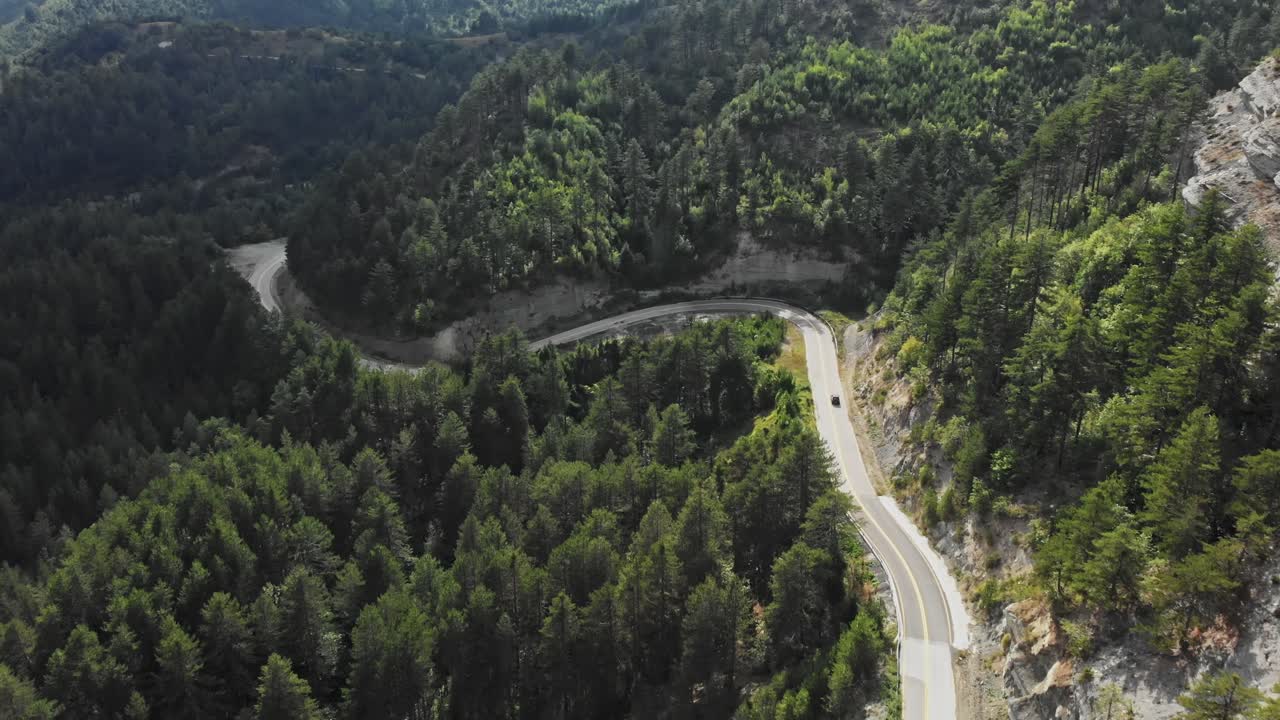 drone video siguiendo coche gran altitud montaña camino sinuoso plano general bosque de pinos gramos