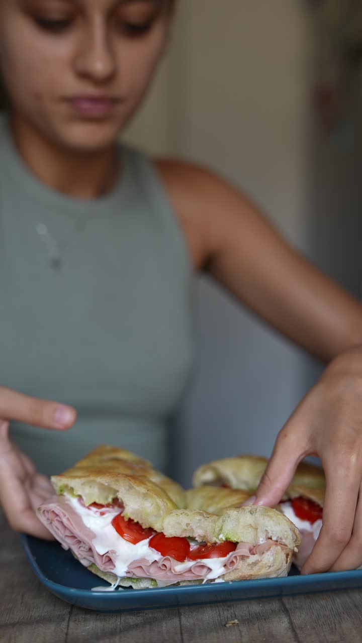 una mujer joven disfrutando de un sándwich casero.