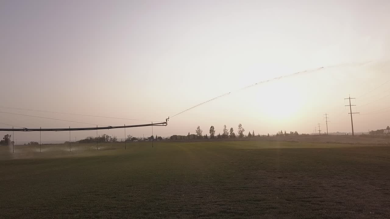 Huge water pressure drives pivot irrigation on crop field near sunset