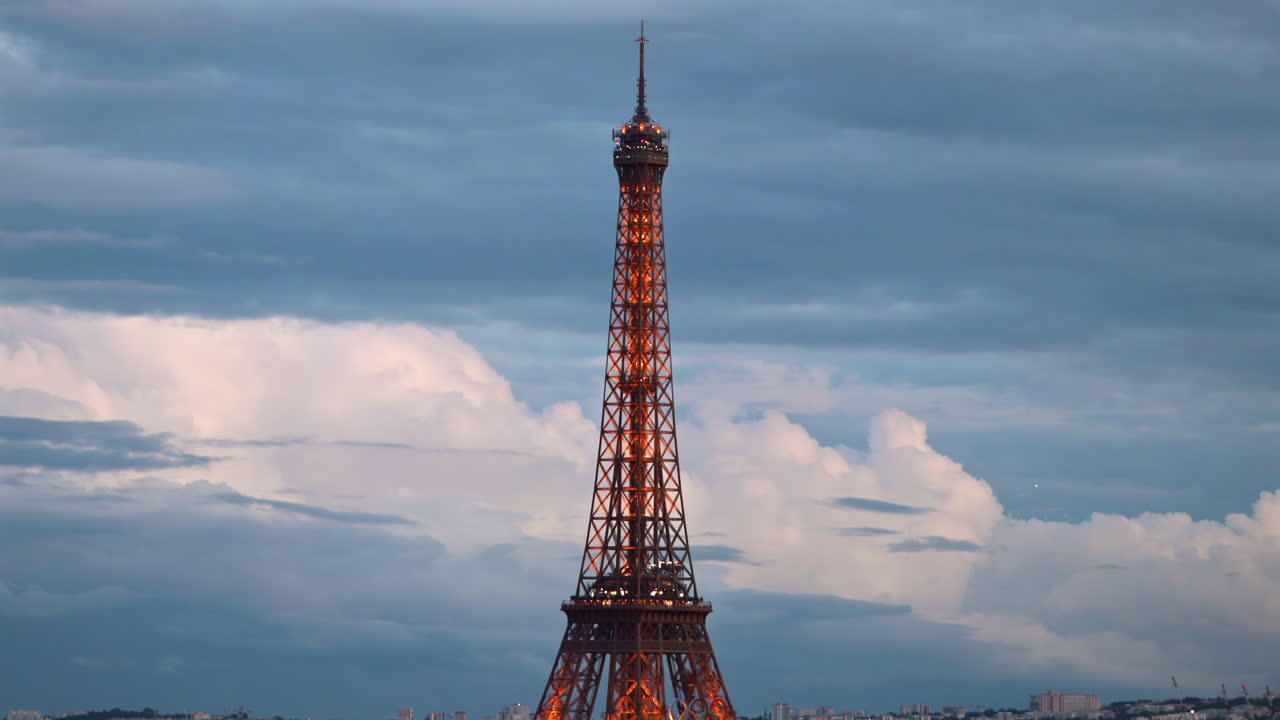Distant view of the Eiffel Tower sparkling in the evening with buildings surrounding it in Paris, France
