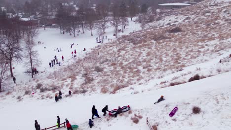 aerial shot of a kid sledding down the side of a hill and wiping out