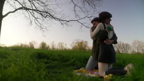 dos mujeres abrazadas en un parque.