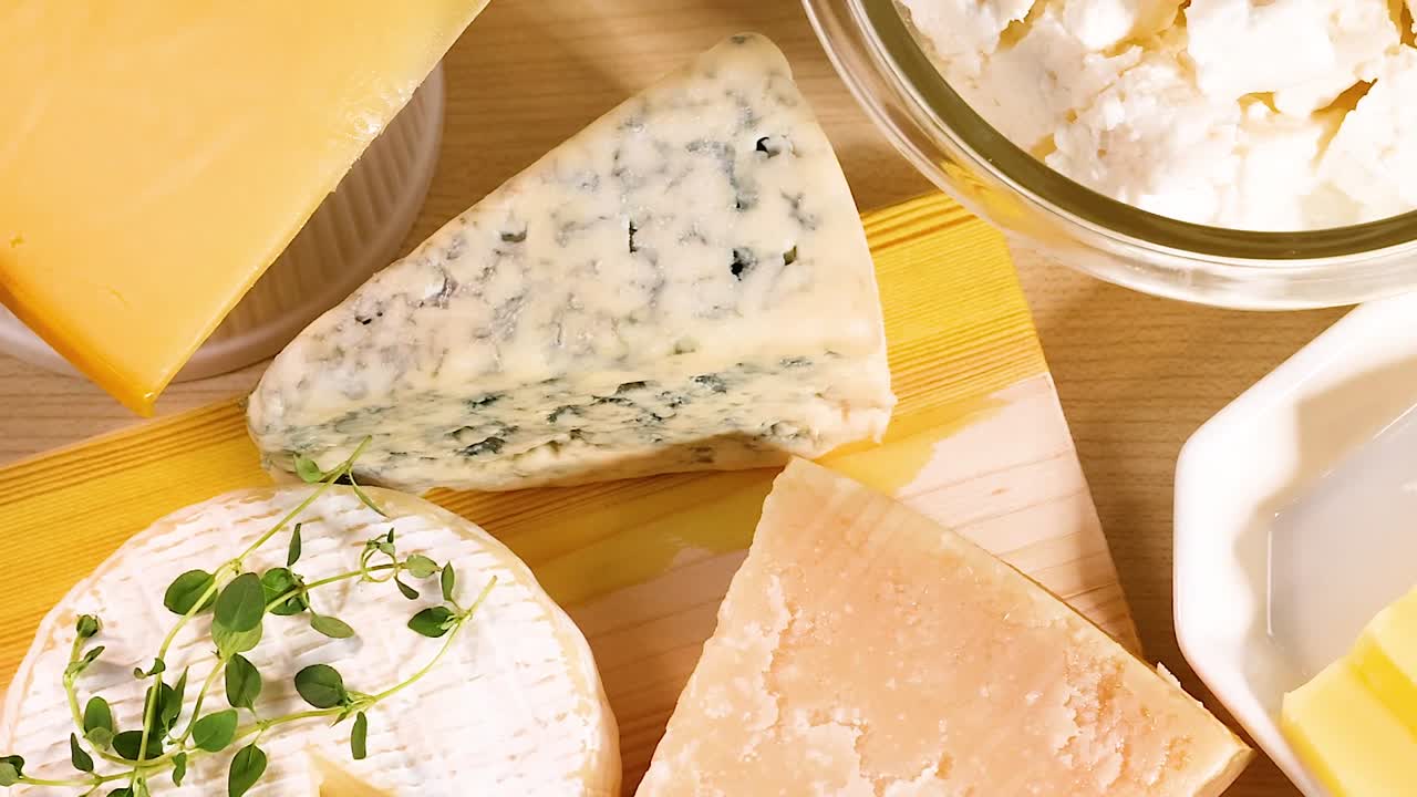 A selection of various cheeses and yogurt jars arranged on a wooden surface.