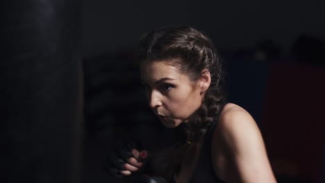 young woman in boxing gloves training with a punching bag in a boxing club