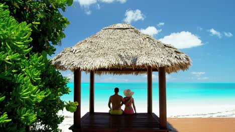 caucasian family sitting in a tiki beach hut