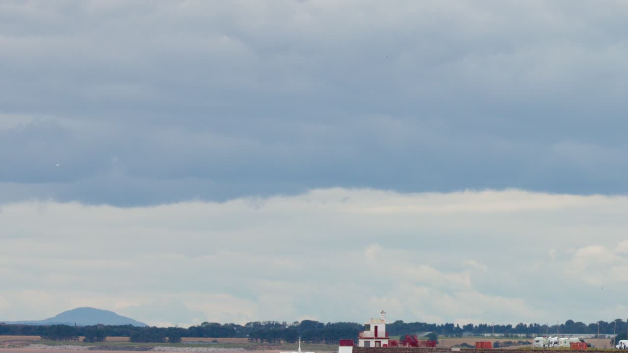 Camera pans from seaside village buildings to open coastal landscape under overcast daylight in Dundee