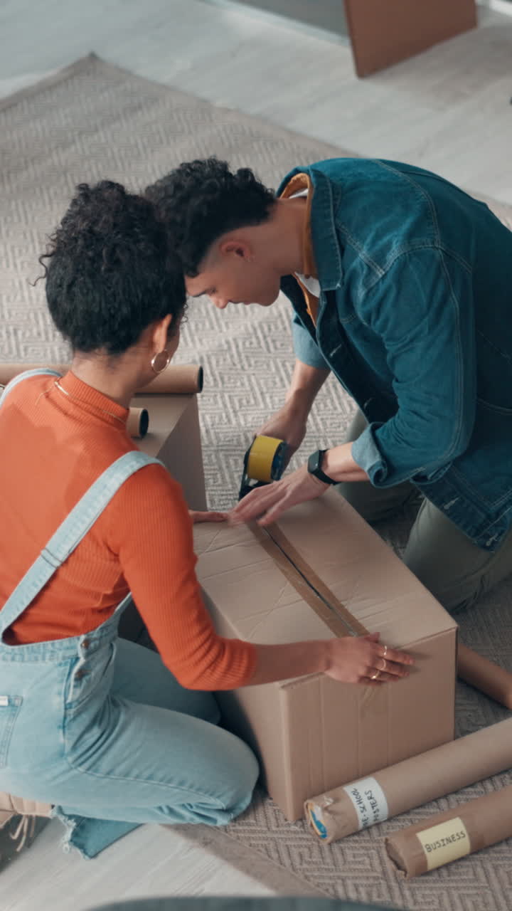 Happy Couple High-Fiving After Taping a Cardboard Box for Moving