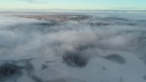 aerial view of white winter landscape and fog above mountain hills, drone shot