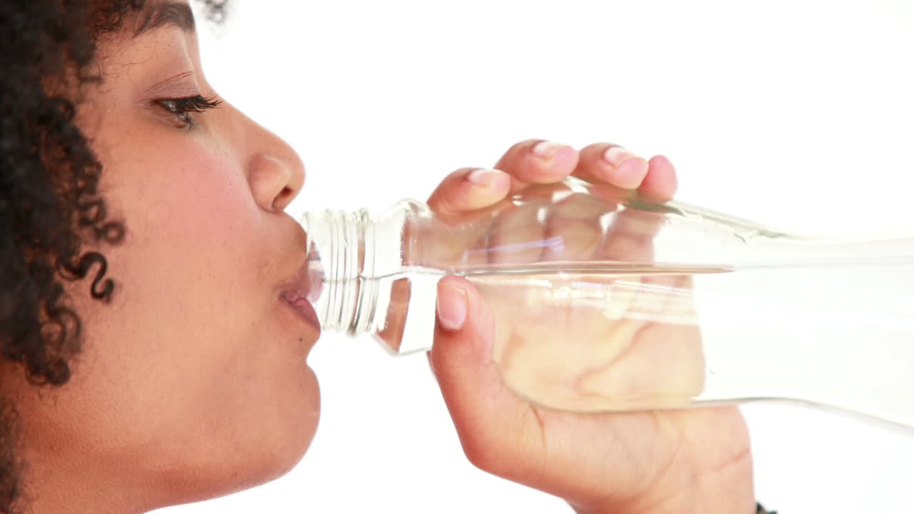 집중된 운동선수 여성이 물을 마시고 있습니다.