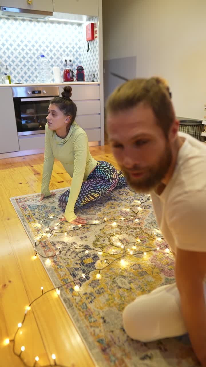 pareja y mujer estirándose en casa con luces de navidad