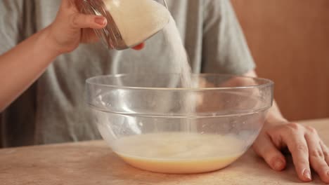 adding sugar to a baking mixture