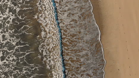 aerial: flying over the breaking waves on the beach