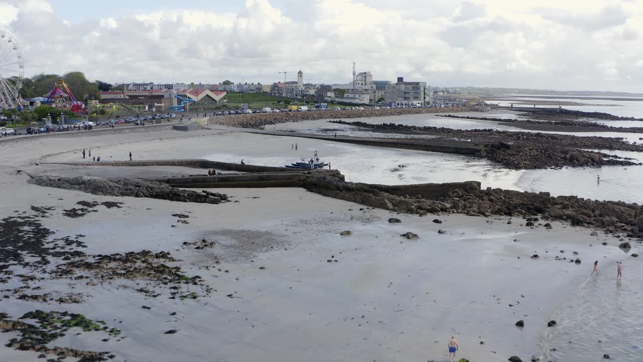 el avión no tripulado se eleva por encima de la línea de agua de la marea baja en ladies beach, revela la costa de galway ireland y el paseo marítimo de salthill