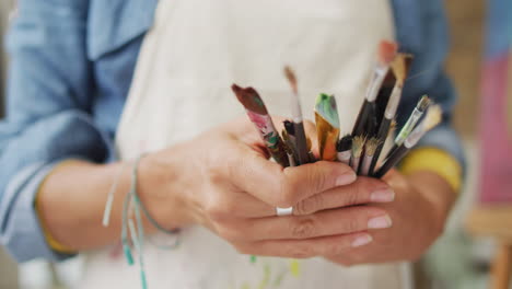 artist's hands holding a variety of paintbrushes, with copy space