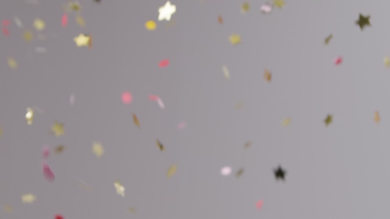 tiro estacionario de confeti dorado y rosa cayendo sobre fondo gris