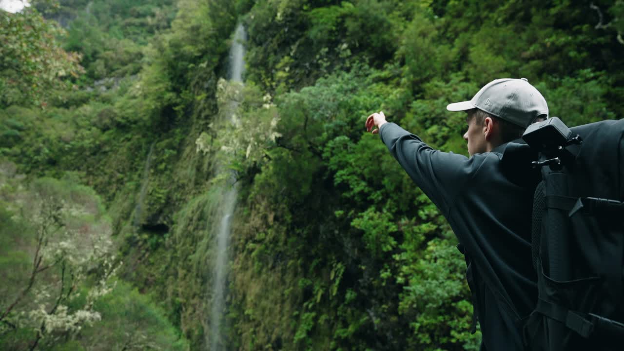 hombre apuntando a la cascada en madeira portugal