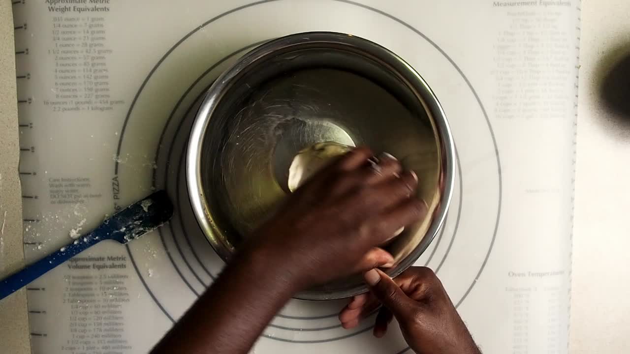 Overhead view of hands put dough in a oil bowl and covered the bowl