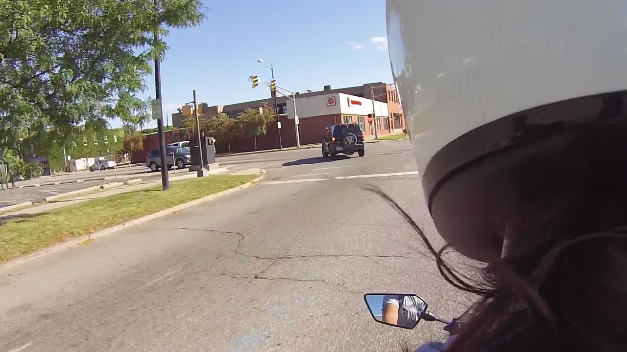 Young woman riding motorcycle down the street on a sunny day