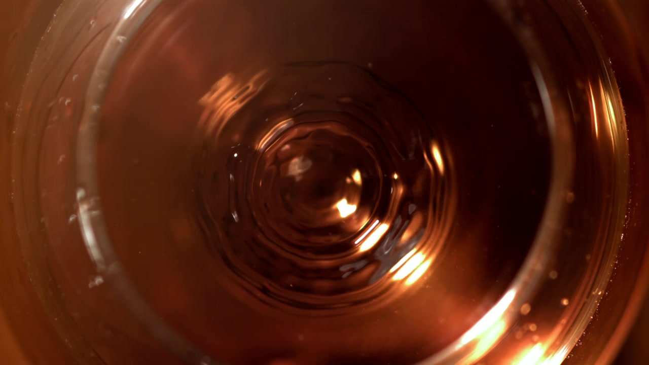 Goccia di liquido dorato che schizza in un bicchiere al rallentatore
