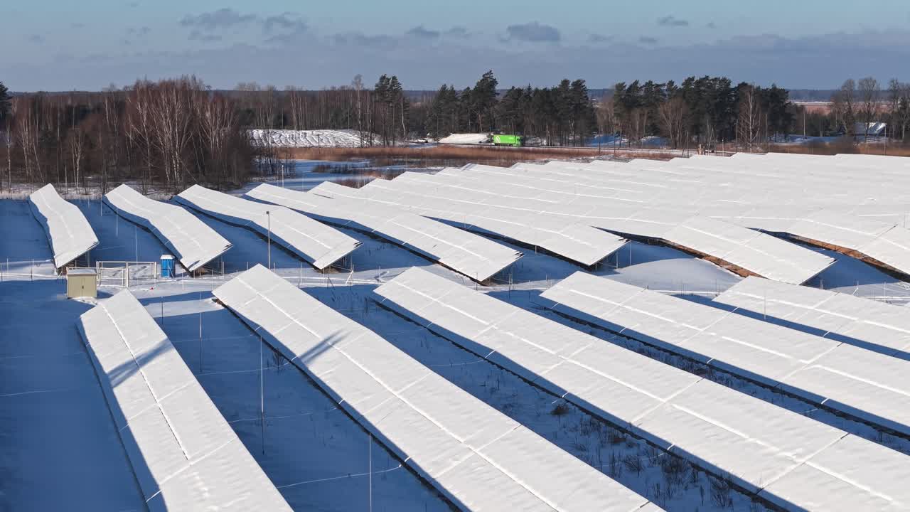 Letecký záběr stoupající nad instalací solárních panelů pokrytých sněhem v zimním zařízení na obnovitelnou energii